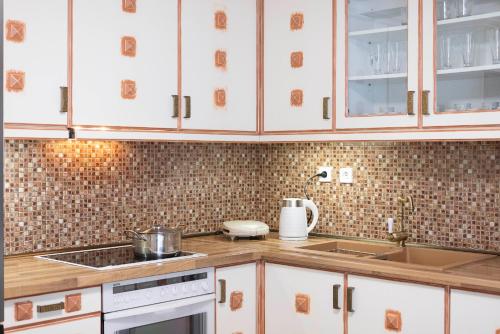 a kitchen with white cabinets and a sink at Roula's Residence in Flogita