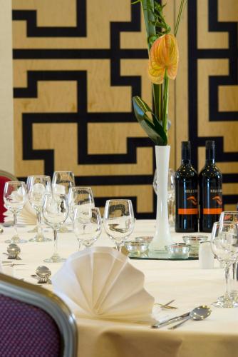 a table with wine glasses and a vase with a flower at Crowne Plaza Liverpool - John Lennon Airport by IHG in Liverpool