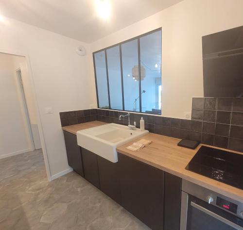 a kitchen with a sink and a large window at Appartement Moderne & Proche Commodités in Toulouse