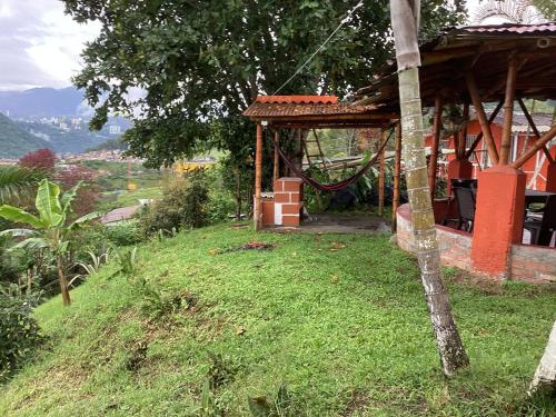 a small house on a hill with a grassy yard at Hostal Las Hamacas Alta 3 in Villamaría