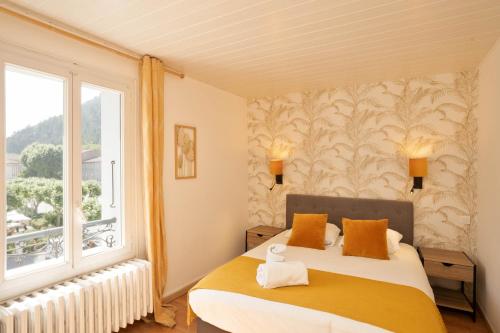 a bedroom with a bed and a large window at Hotel du Levant in Castellane