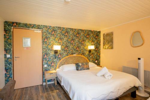 a bedroom with a bed and a floral wall at Hotel du Levant in Castellane