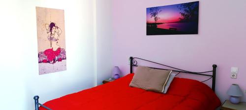 a bedroom with a red bed and a picture on the wall at Gythioflat - Central in Gythio
