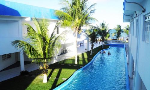 a swimming pool with palm trees in a building at Hotel Chão de Estrelas - Itaparica in Vera Cruz de Itaparica