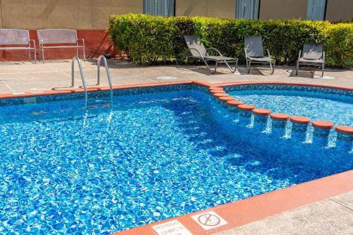 a swimming pool with two chairs at Fiesta Inn Poza Rica in Poza Rica de Hidalgo