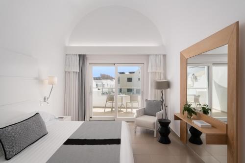 费拉Aressana Spa Hotel & Suites - Small Luxury Hotels of the World的一间带床和椅子的酒店房间