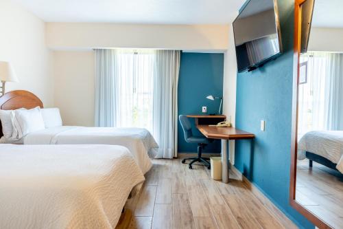 a hotel room with two beds and a desk at Fiesta Inn Poza Rica in Poza Rica de Hidalgo