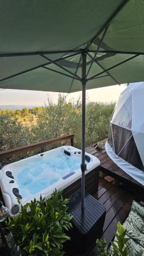 a hot tub sitting on a deck with an umbrella at Logements insolites du Domaine de la Tuilière in Carnoules