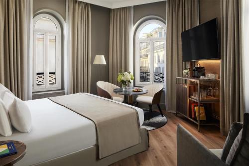 a hotel room with a bed and a table and chairs at NH Collection Paris Ponthieu Champs-Élysées in Paris