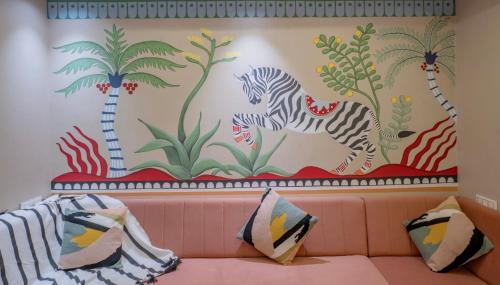 a couch with pillows in front of a mural at Boutique Apartments By One Tree in Jodhpur