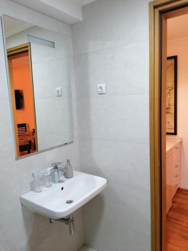 a white bathroom with a sink and a mirror at Apartments 135 in Vršac