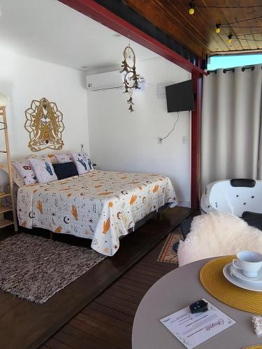a bedroom with a bed and a table and a tv at Chalés Recanto dos Sonhos in Camanducaia