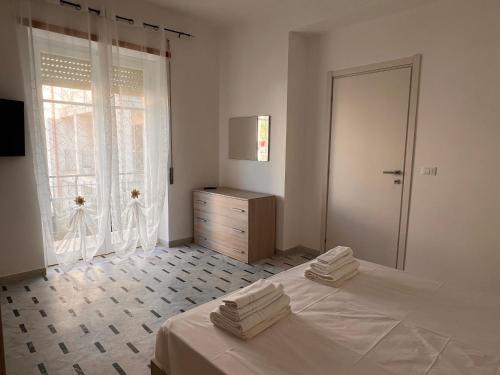 a white bedroom with a bed and a window at Nerissa in Marina di Fuscaldo