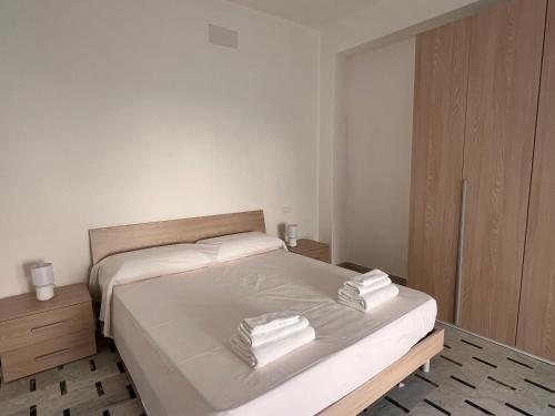 a bedroom with a bed with white sheets and towels at Nerissa in Marina di Fuscaldo