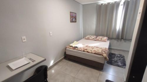 ein kleines Schlafzimmer mit einem Bett und einem Waschbecken in der Unterkunft Kitnet independente confortável e muito bem localizada in Belo Horizonte
