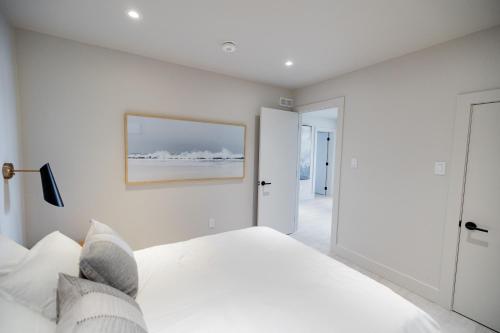 a white bedroom with a bed and a picture on the wall at Lakeview House by Leavetown Vacations in Lakefield