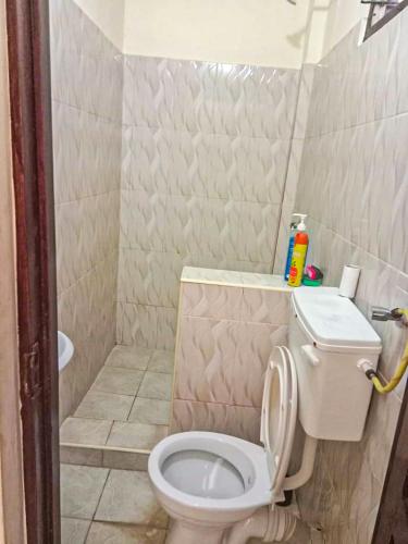 a bathroom with a white toilet and a shower at milina homes in Ukunda