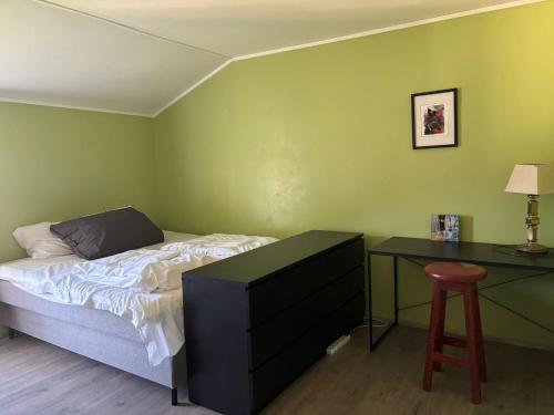 a bedroom with a bed and a desk and a stool at Kræmmervika Rorbuer - Rustic Cabins & Hostel in Lofoten in Ballstad