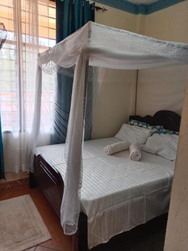 a bedroom with a bed with a canopy at milina homes in Ukunda