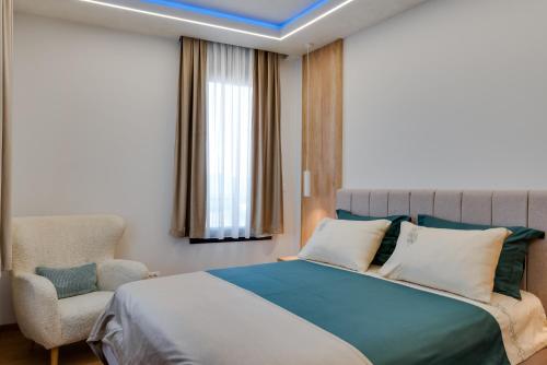 a bedroom with a large bed and a chair at In lux spa apartman 2 in Vrnjačka Banja
