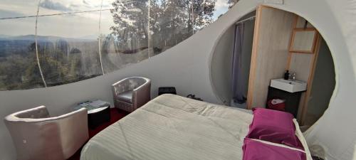 a bedroom with a bed and a large window at Logements insolites du Domaine de la Tuilière in Carnoules