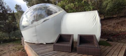 a dome tent with two chairs on a wooden deck at Logements insolites du Domaine de la Tuilière in Carnoules