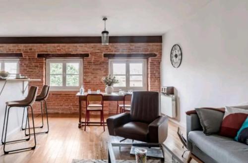 un salon avec un canapé et une table avec des chaises dans l'établissement Le Clos St Georges, à Toulouse