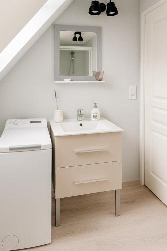 une salle de bain blanche avec un lavabo et un miroir dans l'établissement La maison de la mer, à Criel-sur-Mer