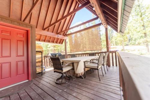 eine Veranda mit einem Tisch, Stühlen und einer roten Tür in der Unterkunft Green Pines Cottage in Duck Creek Village