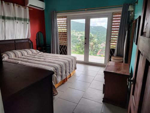 a bedroom with a bed and a large window at Nia's Hillside Apartment - Amazing Scenery in Grande Rivière