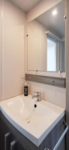 une salle de bain avec un lavabo blanc et un miroir dans l'établissement Temps Suspendu - 7 kms plage - Confort - Lumineux - Détente, à Saint-Hilaire-de-Riez