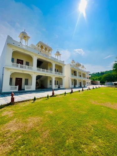 ジャイプールにあるRoop Garh Palace, Jaipurの前方に緑地が広がる白い大きな建物