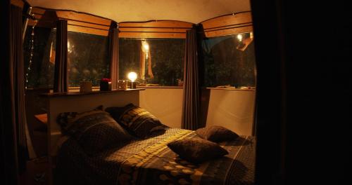 a bedroom with a bed with pillows and two windows at Logements insolites du Domaine de la Tuilière in Carnoules