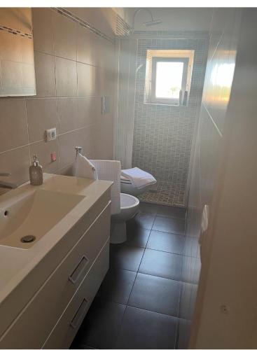 a bathroom with a sink and a toilet and a window at casa mioara in Montefiascone