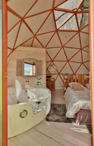 a room with a tub and a bed in a tent at Logements insolites du Domaine de la Tuilière in Carnoules