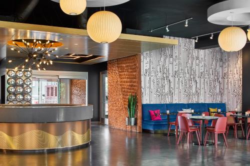 a dining room with tables and chairs and lights at Aloft Raleigh in Raleigh