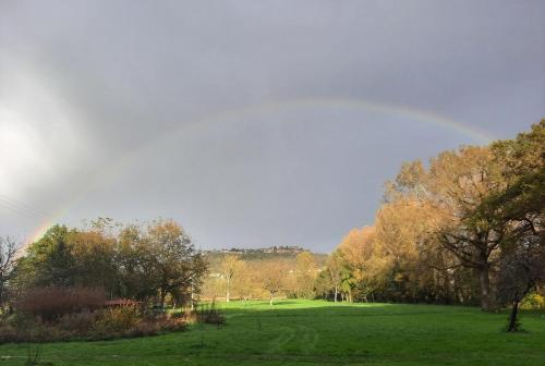 a rainbow in the sky over a field with trees at Gîte exceptionnel au bord de la rivière Lot in Capdenac-Gare