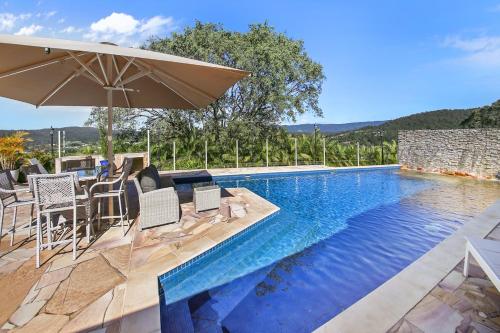 a swimming pool with chairs and an umbrella next to it at Amrata Estate in Samford