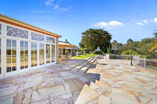 a stone patio with a building and a fence at Amrata Estate in Samford