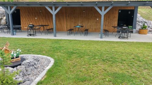 a covered patio with tables and chairs and grass at Rezort pod Roháčmi in Vitanová