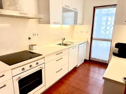a white kitchen with a sink and a stove at Casa Mareta in Sagres