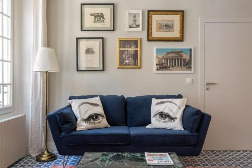 - un canapé bleu dans le salon avec des photos sur le mur dans l'établissement Strada - Furnished apartment - Downtown Lyon, à Lyon