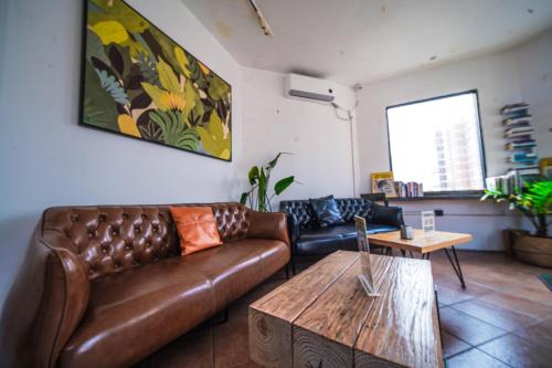 a living room with a brown leather couch and a table at Chengdu Local Tea Hostel - Short Walk To Taikooli - Chill & Social Coffee Lounge - Metro downstairs - Free Activities - Friendly English Speaking Staff - Tibet, Panda, Buddha & Snow Mountain Tours in Chengdu