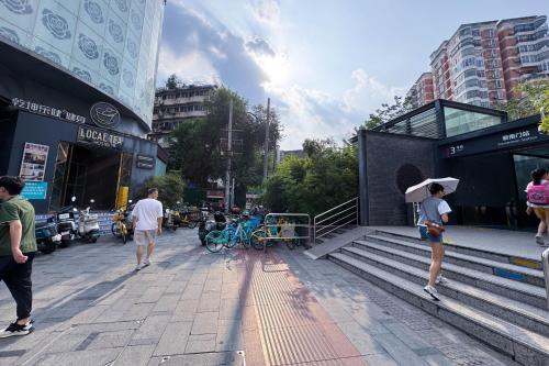 a woman with an umbrella walking down a street at Chengdu Local Tea Hostel - Short Walk To Taikooli - Chill & Social Coffee Lounge - Metro downstairs - Free Activities - Friendly English Speaking Staff - Tibet, Panda, Buddha & Snow Mountain Tours in Chengdu