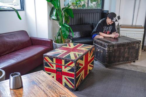 a man sitting in a living room next to a box at Chengdu Local Tea Hostel - Short Walk To Taikooli - Chill & Social Coffee Lounge - Metro downstairs - Free Activities - Friendly English Speaking Staff - Tibet, Panda, Buddha & Snow Mountain Tours in Chengdu