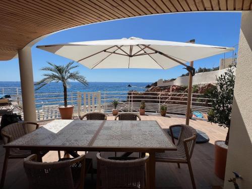une table et des chaises avec un parasol et l'océan dans l'établissement Casa Marina, à Saint-Raphaël