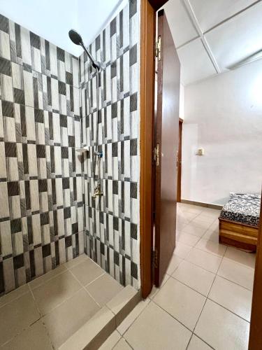 a bathroom with a shower with a tile wall at Résidence Agbevivi in Aného