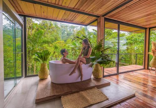a man and woman sitting in a bath tub on a porch at Suite Alpayaku, Suite Boutique Privada con Desayuno Incluido, Cedro Amazon Lodge in Mera