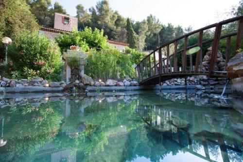 a bridge over a body of water with a body of water at Logements insolites du Domaine de la Tuilière in Carnoules