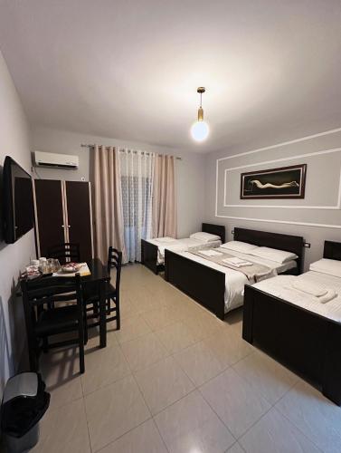 a hotel room with two beds and a table and chairs at Vila Zhiti in Durrës